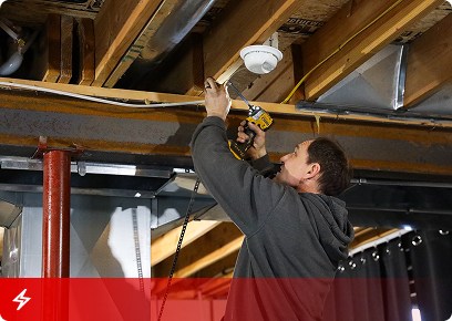 Electrical CTA KB Complete technician installing a light fixture between basement floor joists