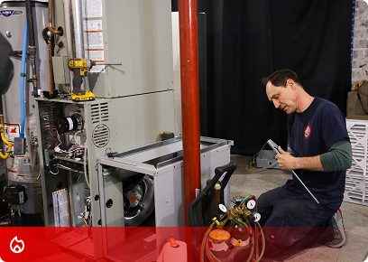 KB Complete Heating CTA KB Complete technician kneeling to service a furnace with a gauge set