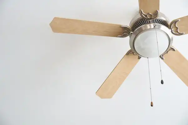 A blonde ceiling fan with a light 