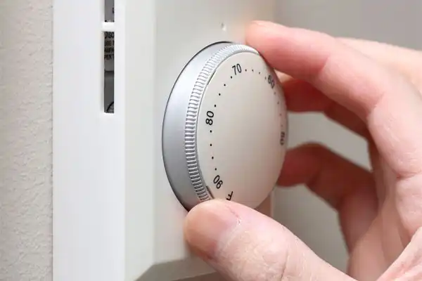 Closeup of person adjusting a wall thermostat 