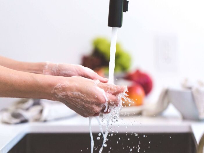 Closeup of someone washing their hands in a kitchen sink