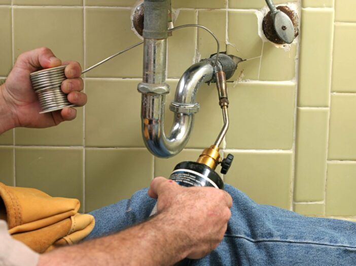Closeup of someone performing a drain clearing underneath a sink