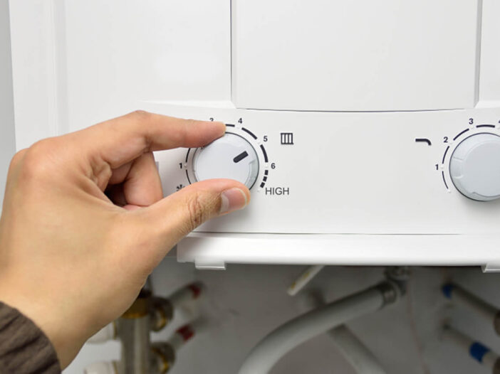 Closeup of someone adjusting a water heater dial